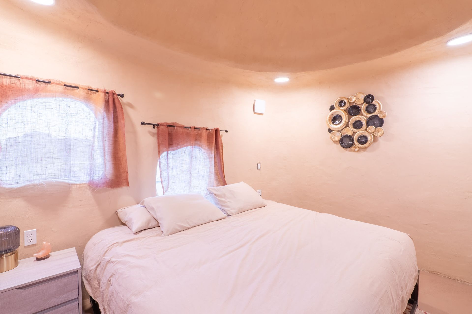 A bedroom with a bed , nightstand , and two windows.