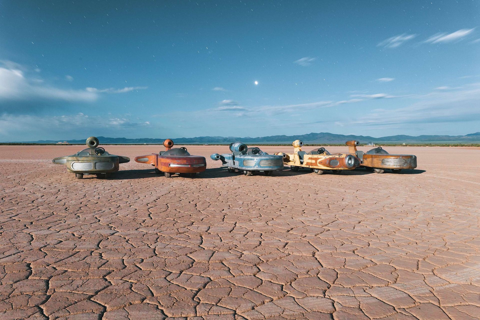 A row of cars are parked in the middle of a desert.