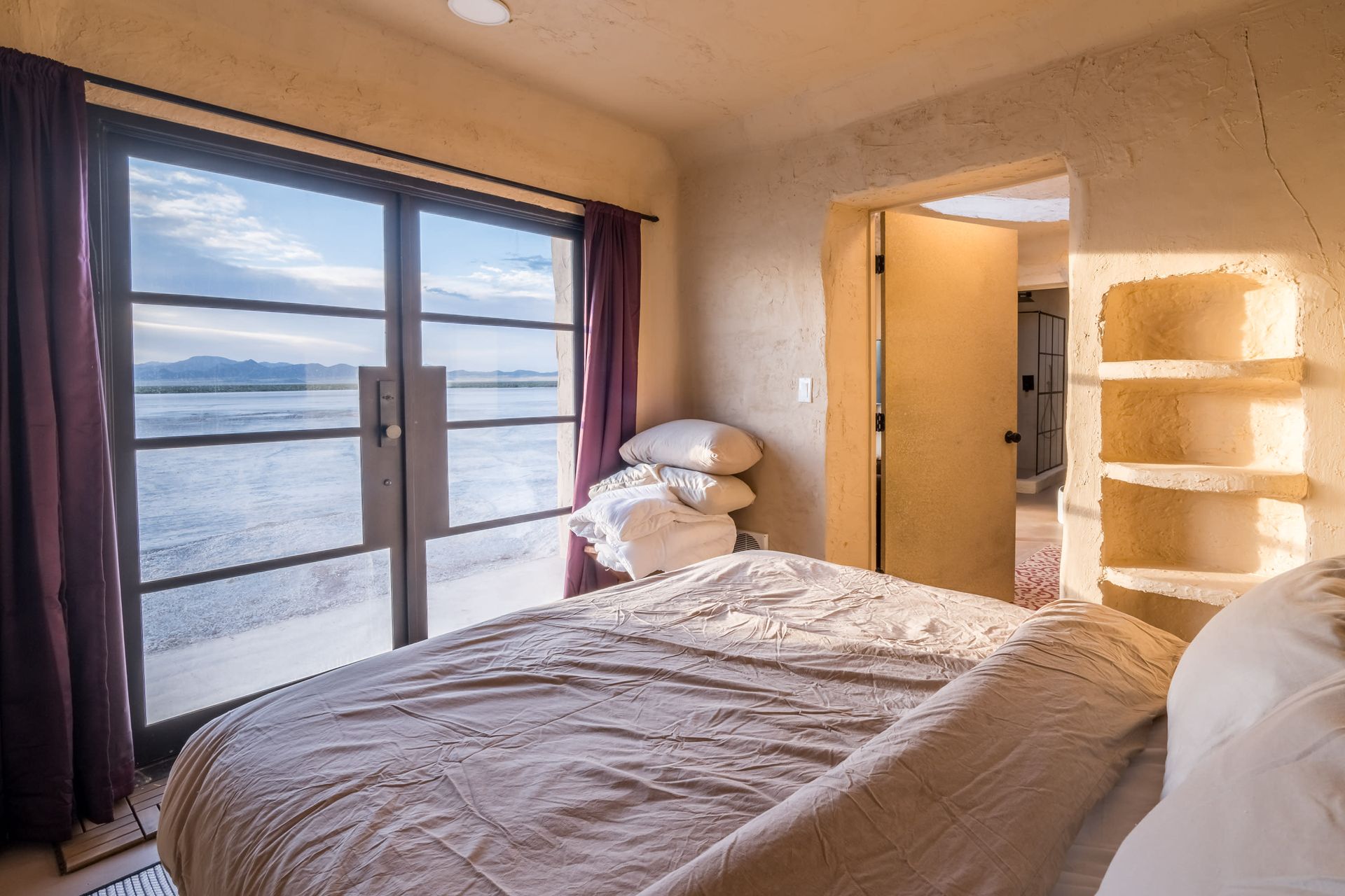 A bedroom with a bed , sliding glass doors and a view of the ocean.