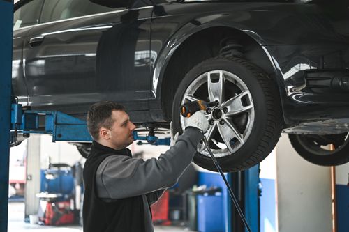 An auto mechanic working on a car tire rotation. An auto mechanic working on a car tire rotation.