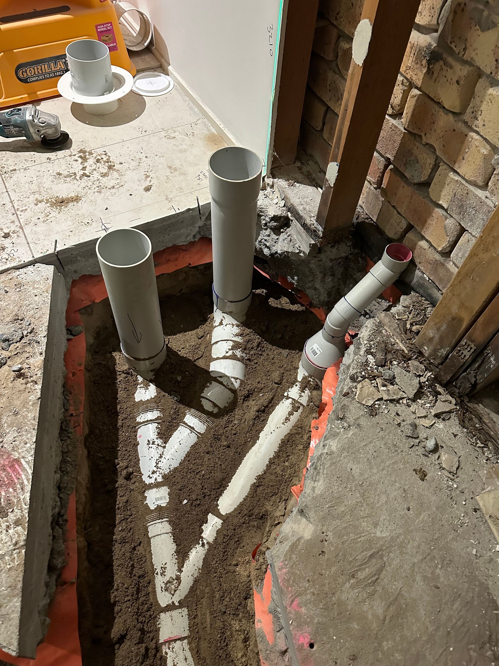 Plumbing Pipes in a Trench, Orange Barrier Lining the Sides — Vantage Plumbing and Drainage In Coomera, QLD