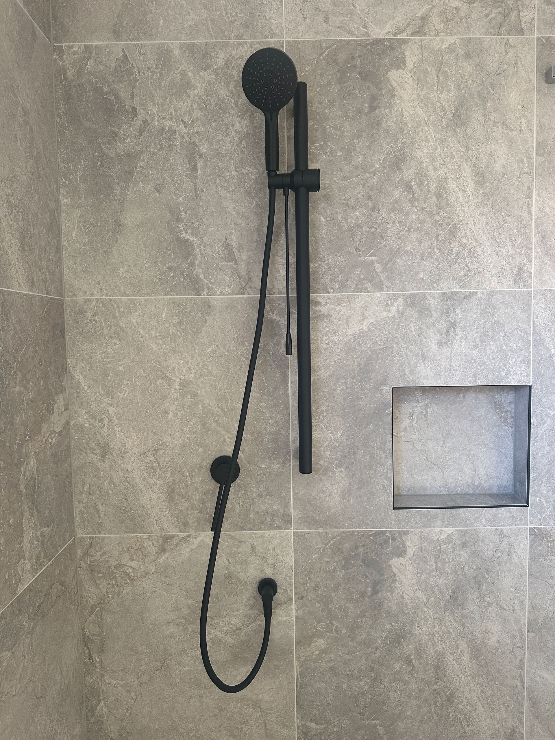 Black Shower Head and Adjustable Bar on Tiled Wall — Vantage Plumbing and Drainage In Pacific Pines, QLD