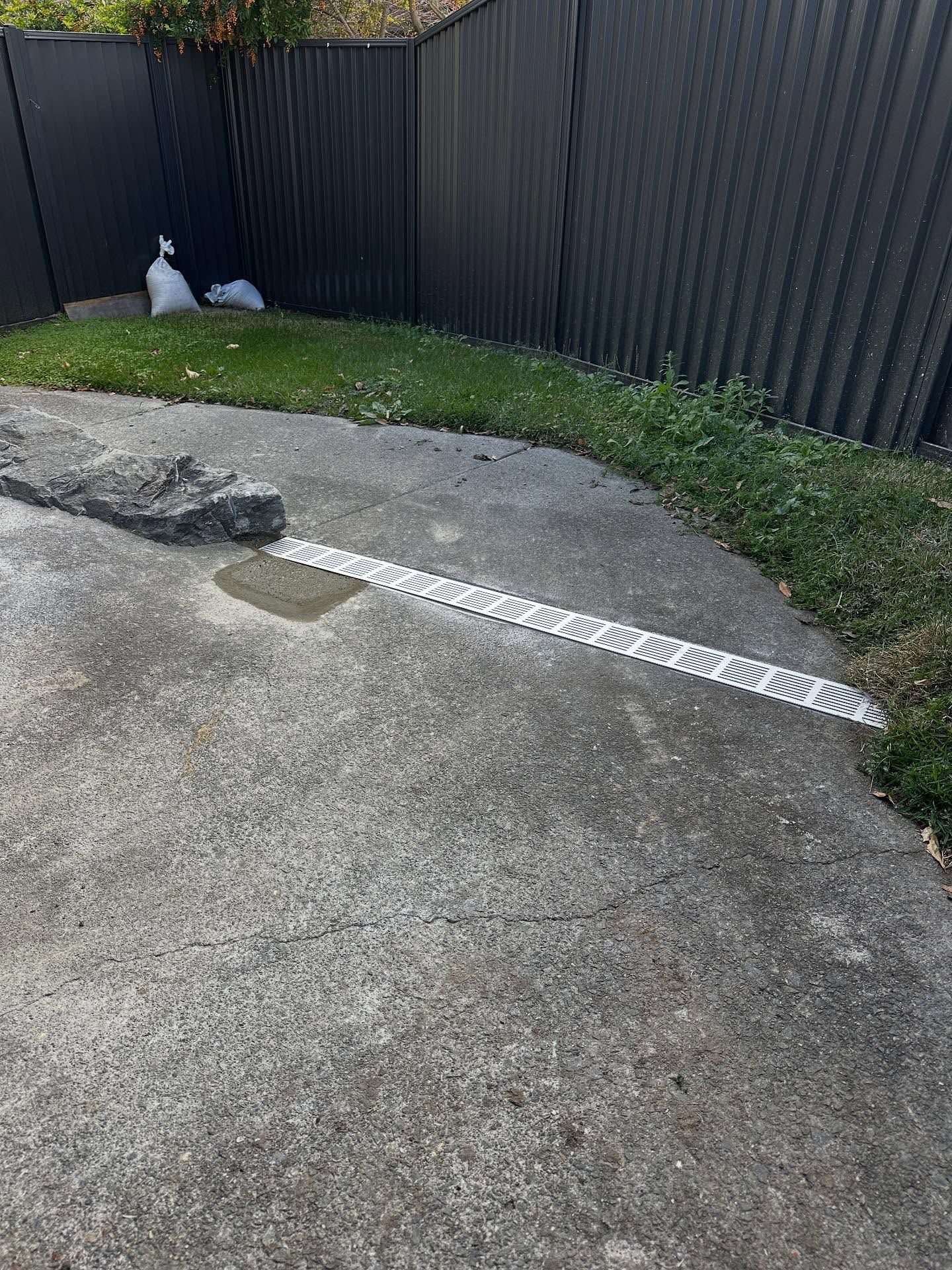 Concrete Driveway With a Drainage Grate and Grass — Vantage Plumbing and Drainage In Coomera, QLD