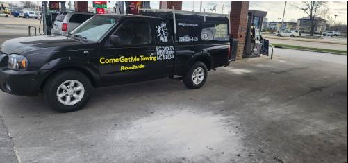 A tow truck is towing a gray car on the side of the road.