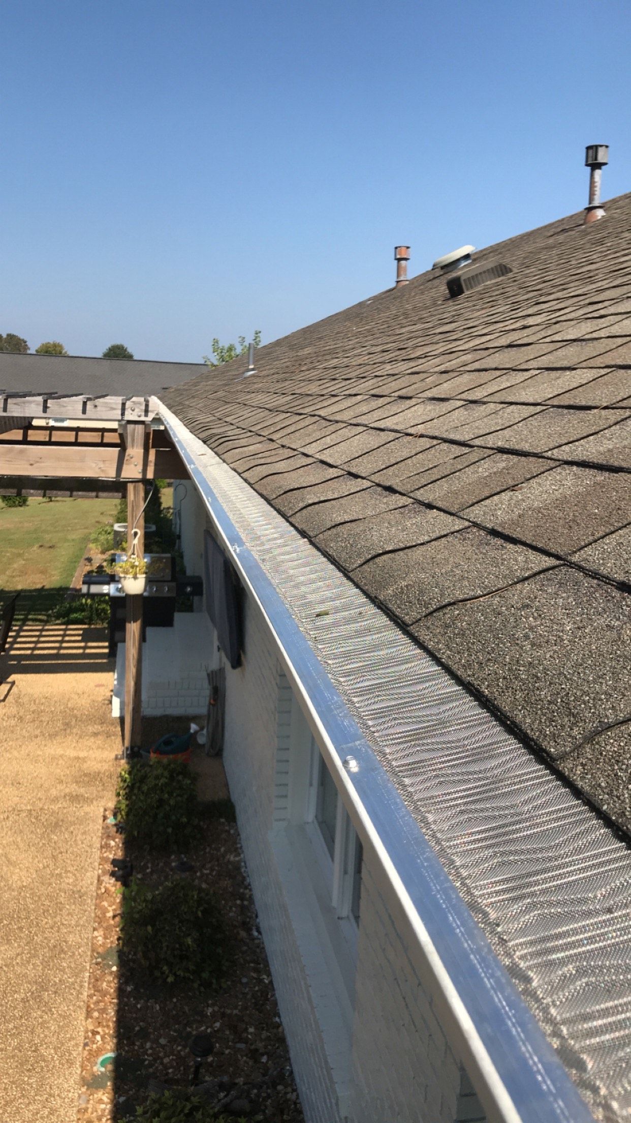 Gutters along a roofline with a deck in the background on a sunny day.