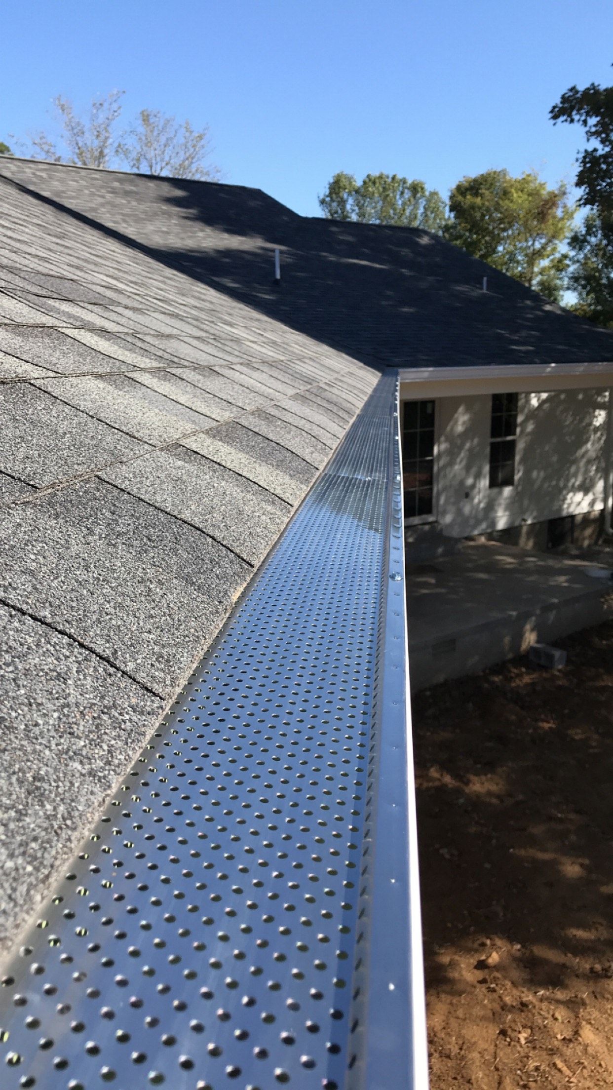 Close-up of a house's roof and gutter with metal screen, protecting against debris.
