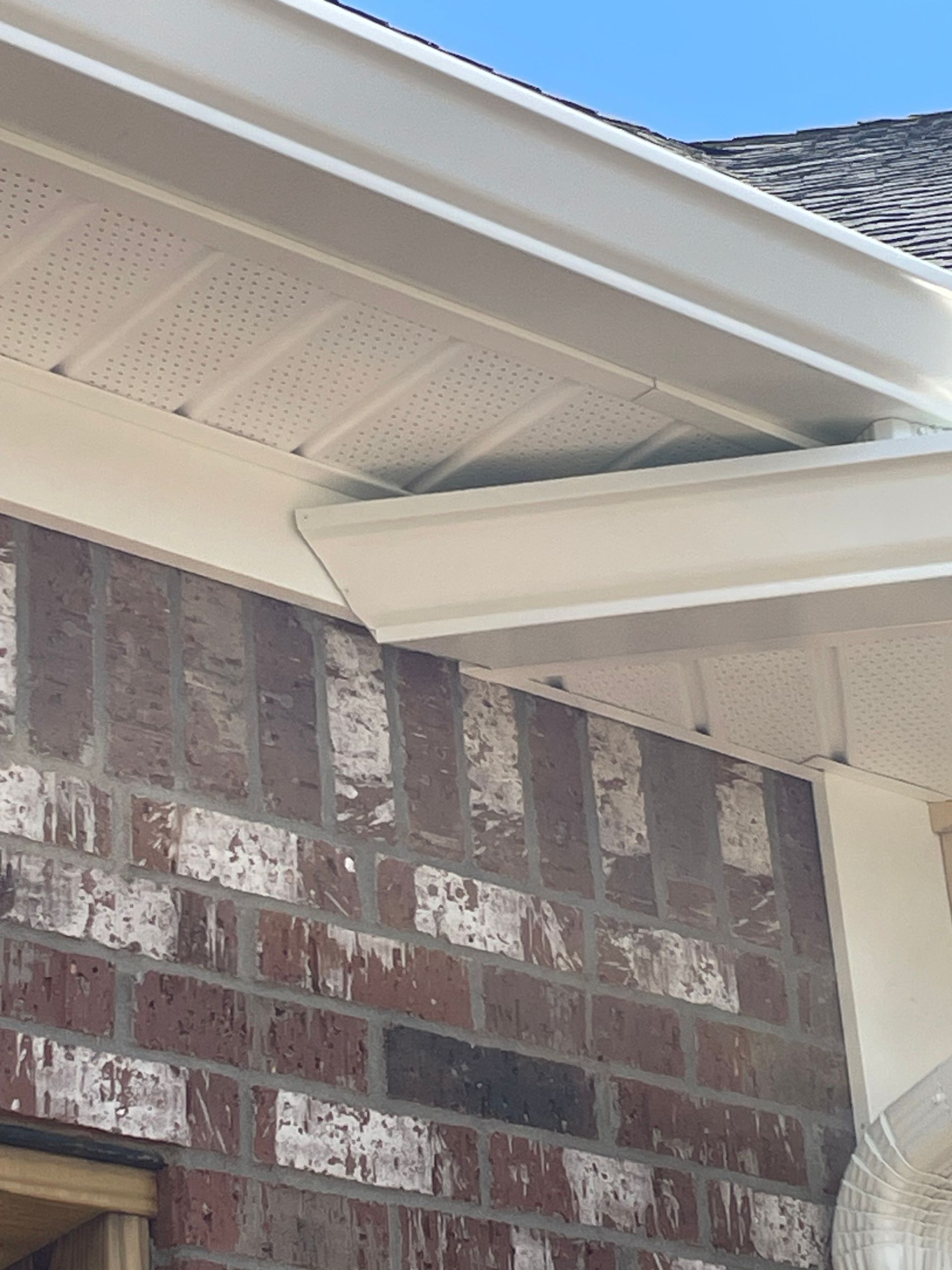 Brick wall and white soffit with dark mildew staining.