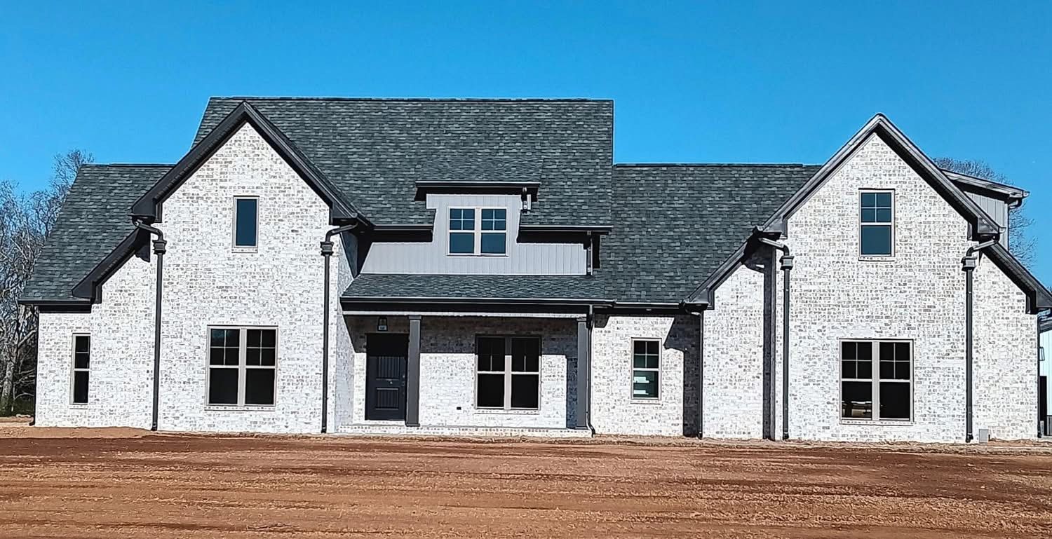 Brick house with gray roof against a blue sky.