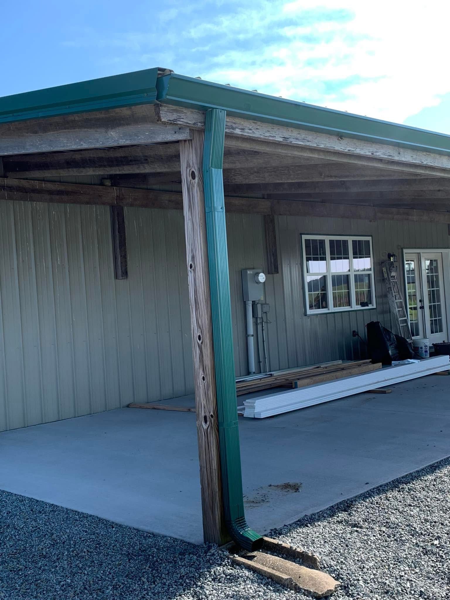 Building with a green roof and a wooden support post covered in green metal.