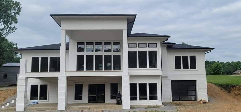 White modern two-story house with many dark framed windows under a cloudy sky.
