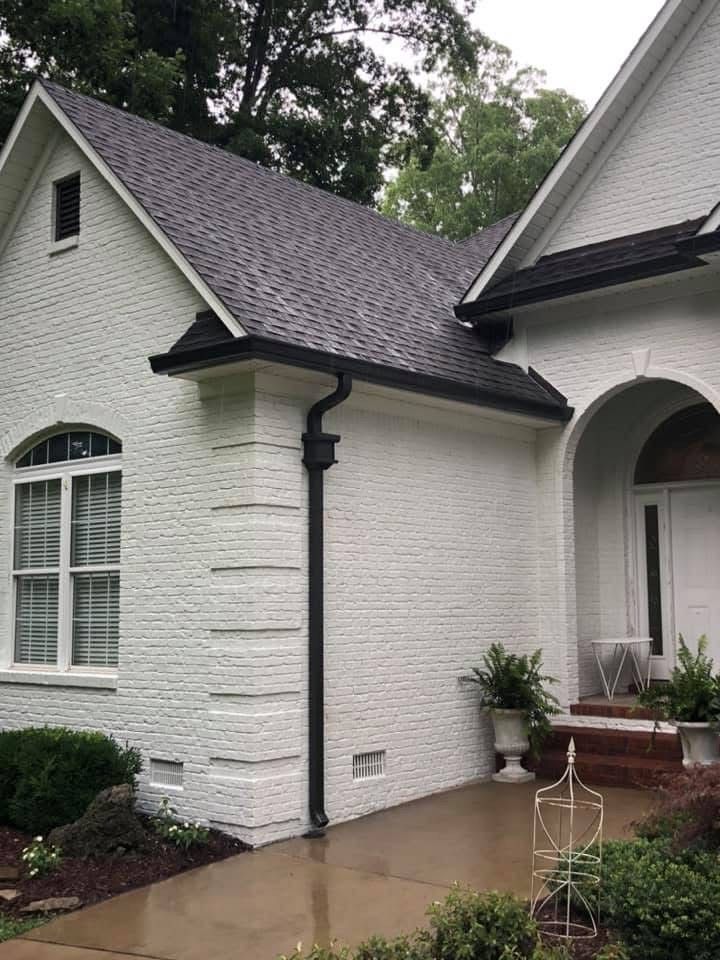 White brick house with black roof, gutters, and trim.