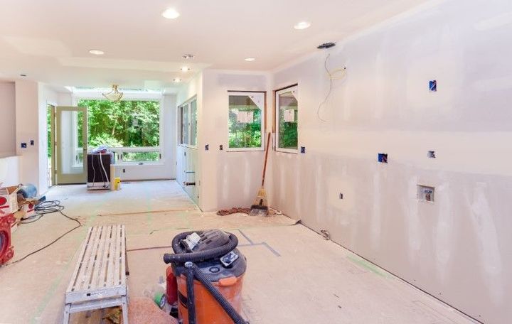 Bright unfinished living room with white walls, recessed lights, and open doors to a green patio