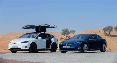Two Tesla electric cars are parked next to each other in the desert.