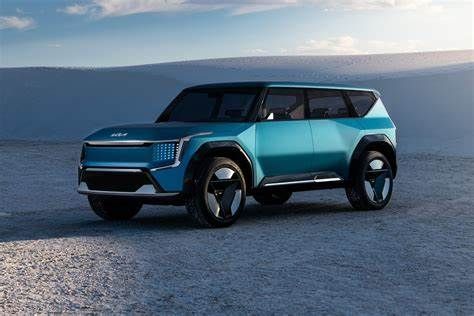 A blue KIA EV9 suv is parked in the middle of a desert.