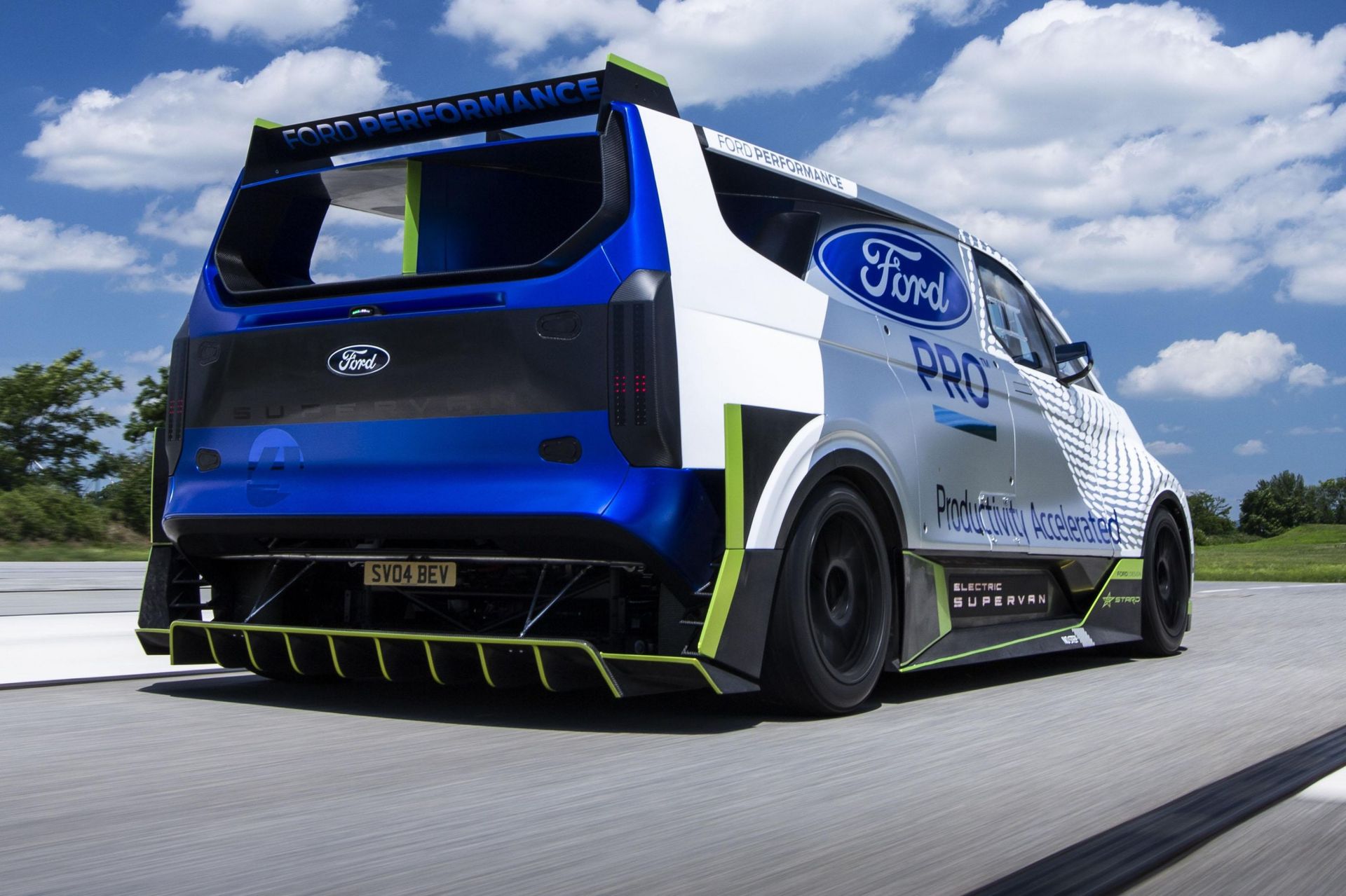 a blue and white electric vehicle ford supervan  is driving down a road