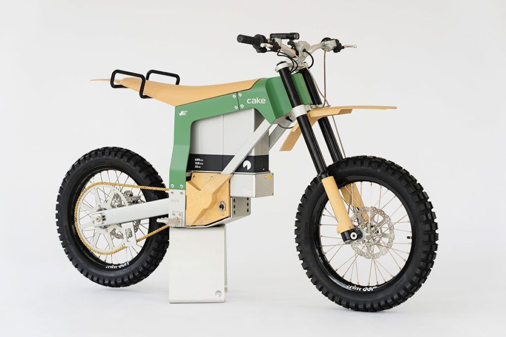 a green and white cake electric vehicle dirt bike is sitting on a white surface. 