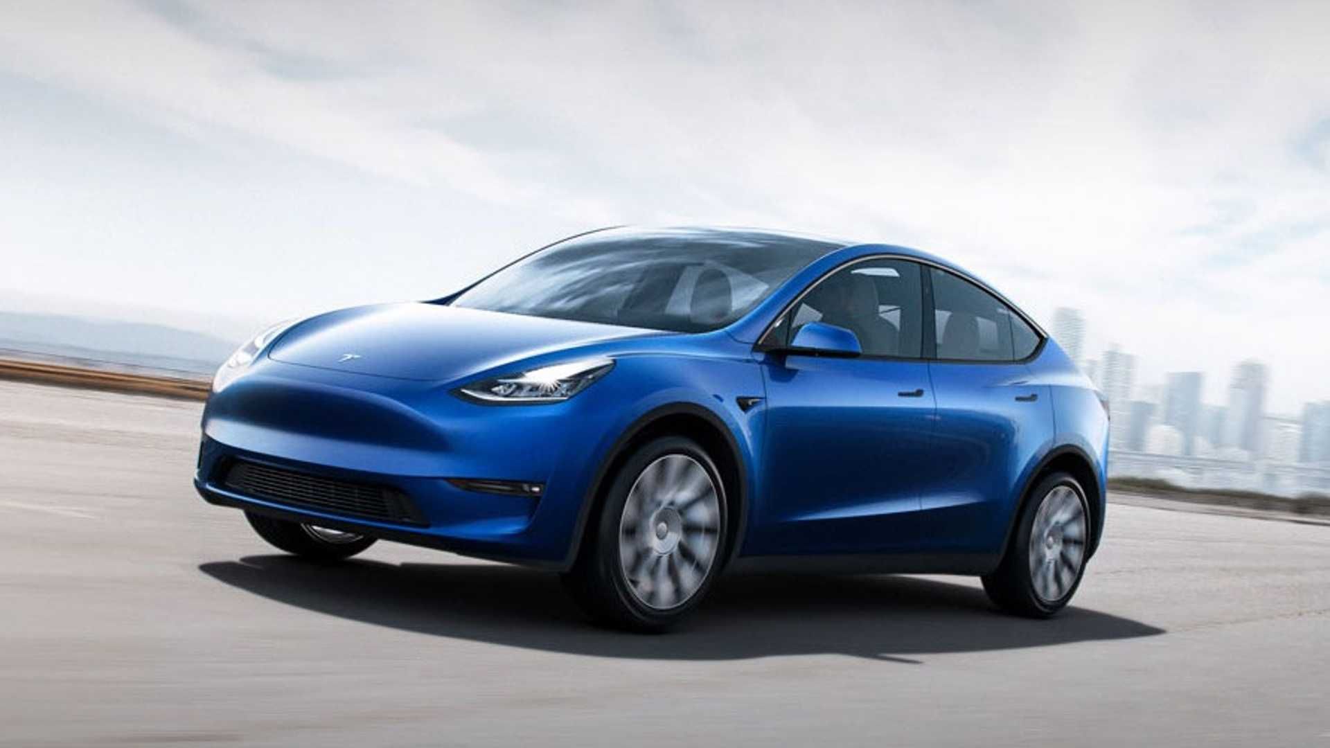 A blue tesla model Y is driving down a road.