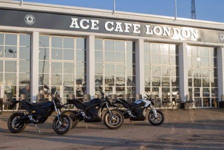 Three motorcycles are parked in front of the Ace Cafe London