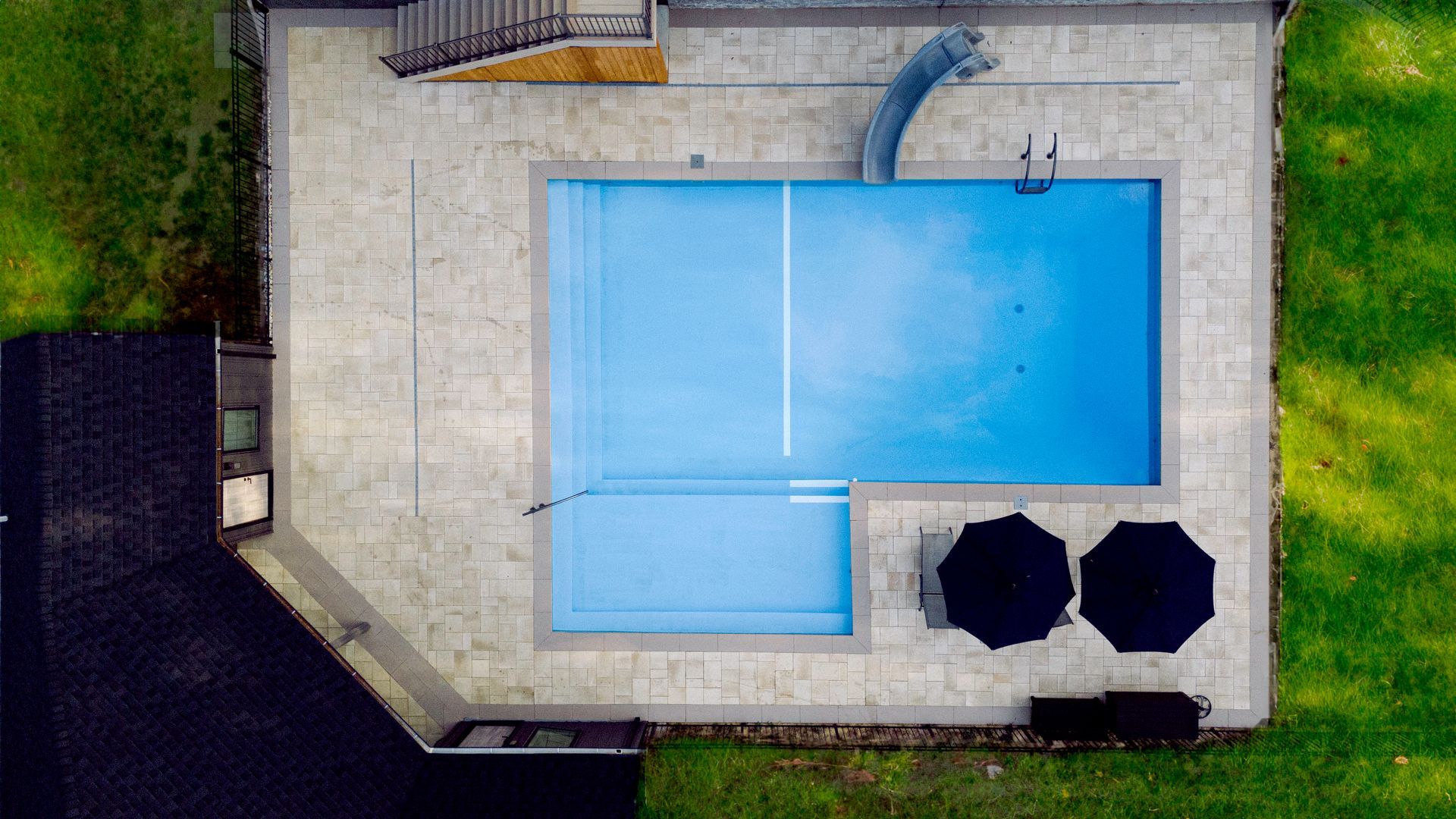 An aerial view of a large swimming pool with two umbrellas.