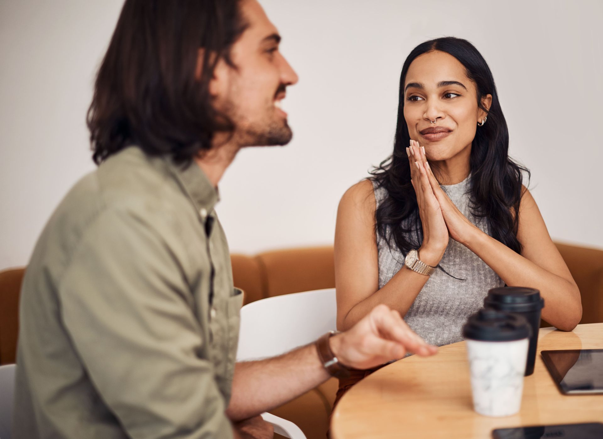 A man and a woman are sitting at a table talking to each other.