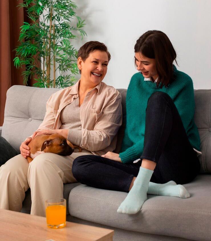 Two women are sitting on a couch with a dog
