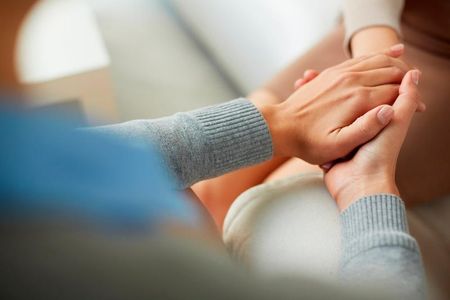 A close up of a person holding another person 's hand.