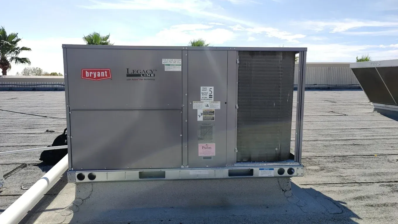 Rooftop HVAC unit on a flat roof. Gray metal with Bryant logo, vents, and service access panel.