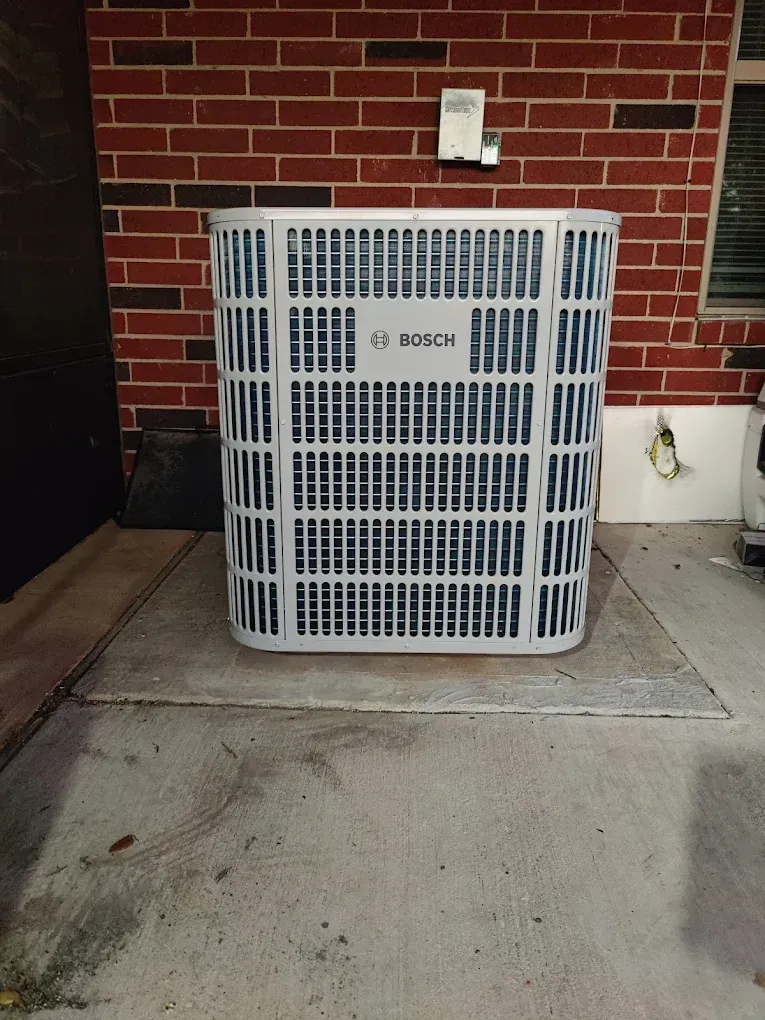 White air conditioning unit against a red brick wall.