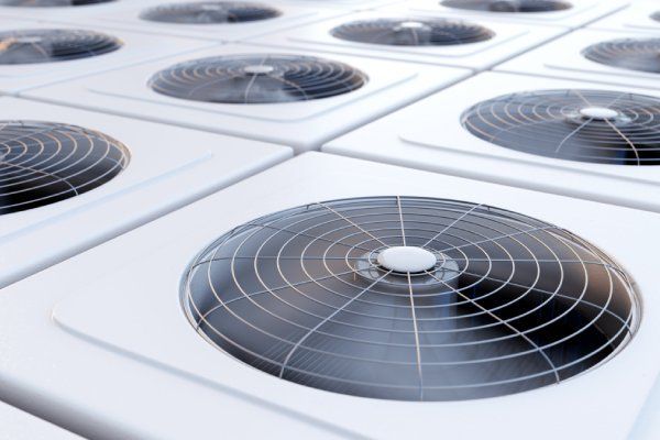 Rows of white rooftop air conditioning units with black fan grilles.