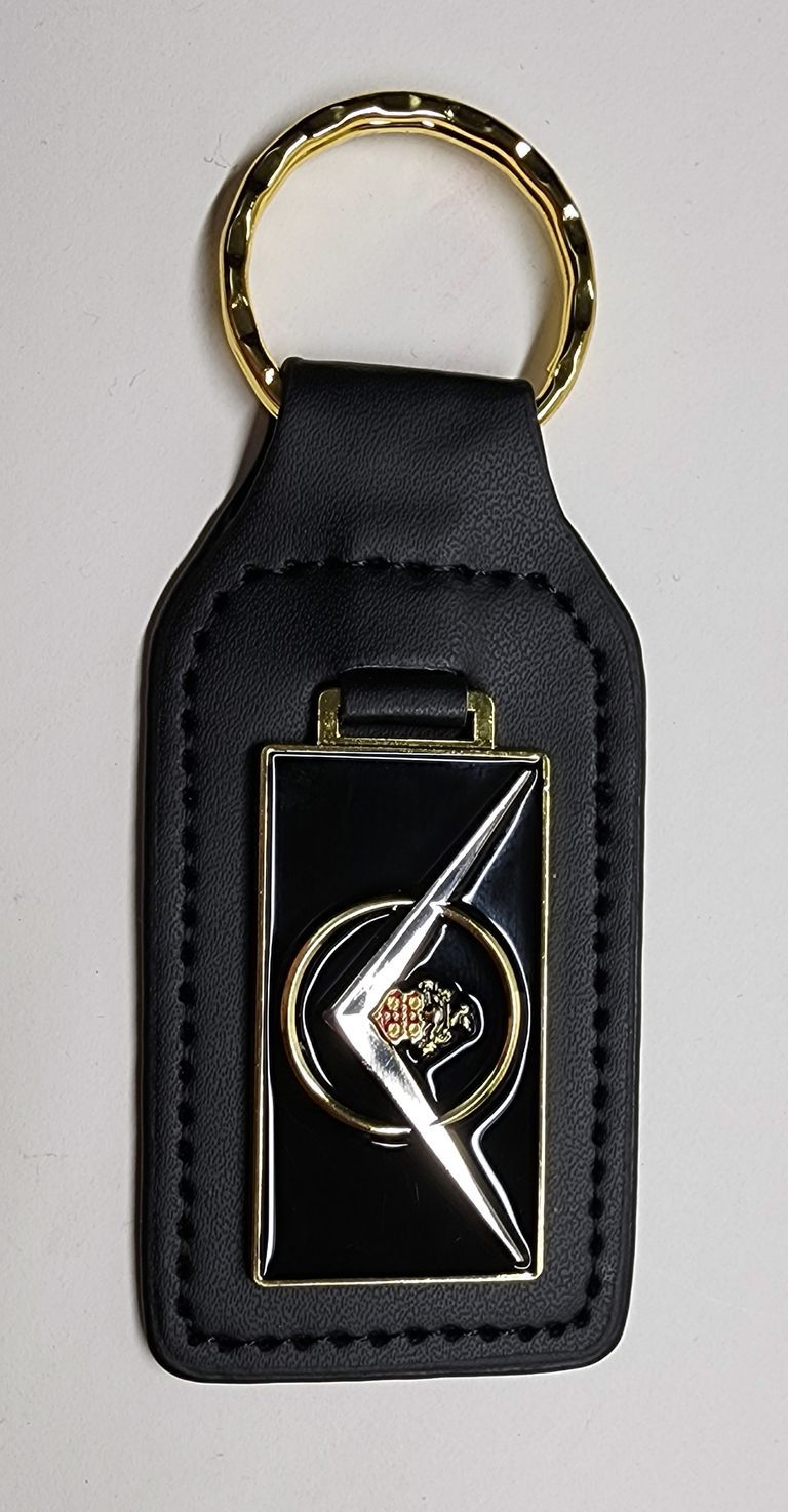 Black leather keychain with gold trim and ring. The decorative emblem has a red shield and gold embellishments.