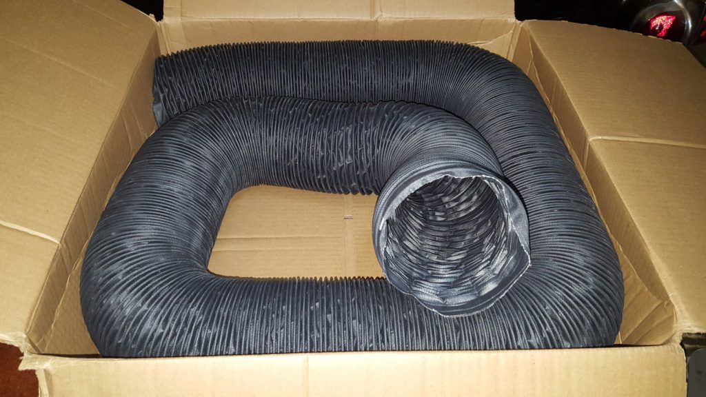 Black, corrugated flexible ducting coiled inside a cardboard box.