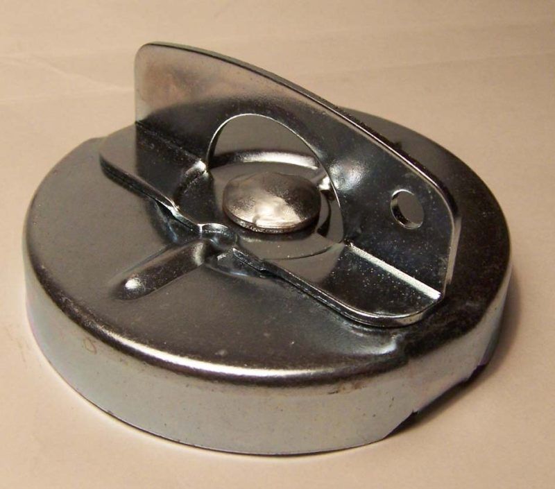 A silver metal fuel tank cap with a handle. The cap is circular with a flat top and a curved handle extending from the center.