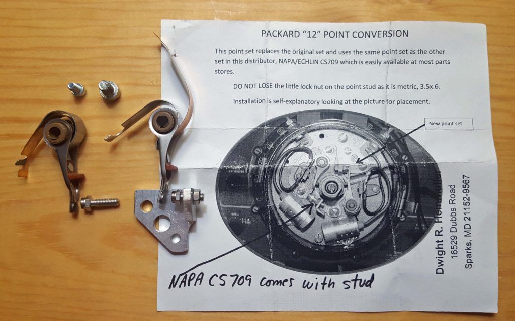 Parts for a Packard distributor points conversion kit, including instructions and components, on a wooden surface.