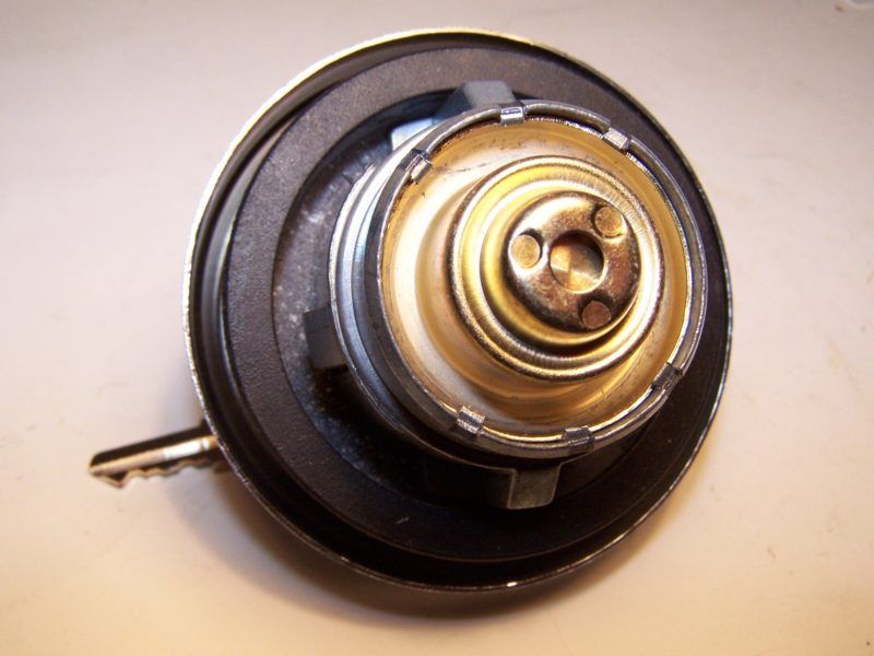 Close-up of a fuel cap, showing a black rubber seal and metallic components.