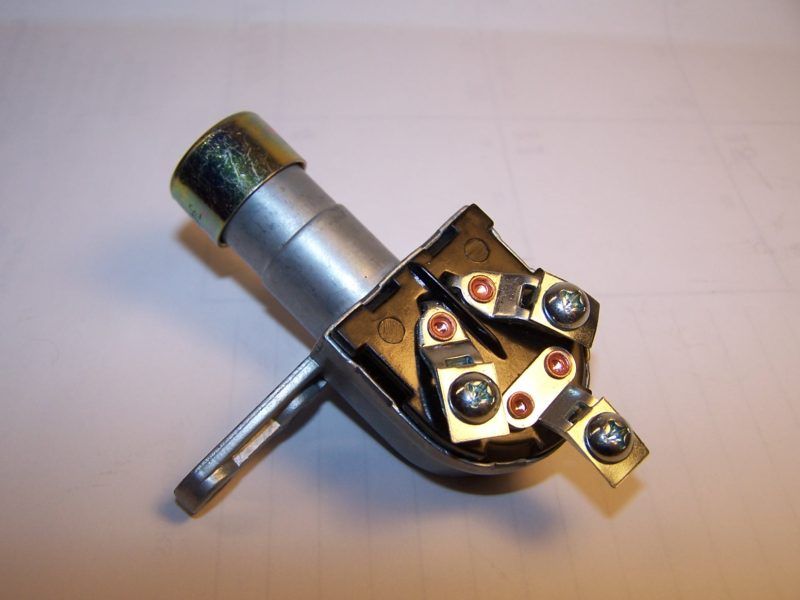 Silver ignition switch with exposed terminals, resting on a white surface.