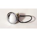Chrome toilet flush button with a white, teardrop-shaped center and a black rubber tube attached.