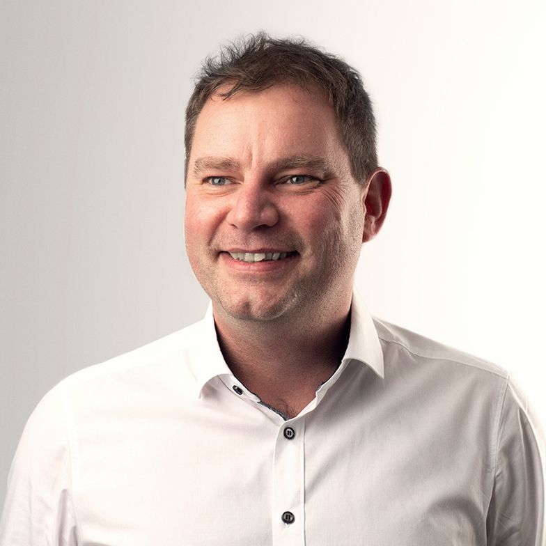 A man in a white shirt is smiling for the camera.