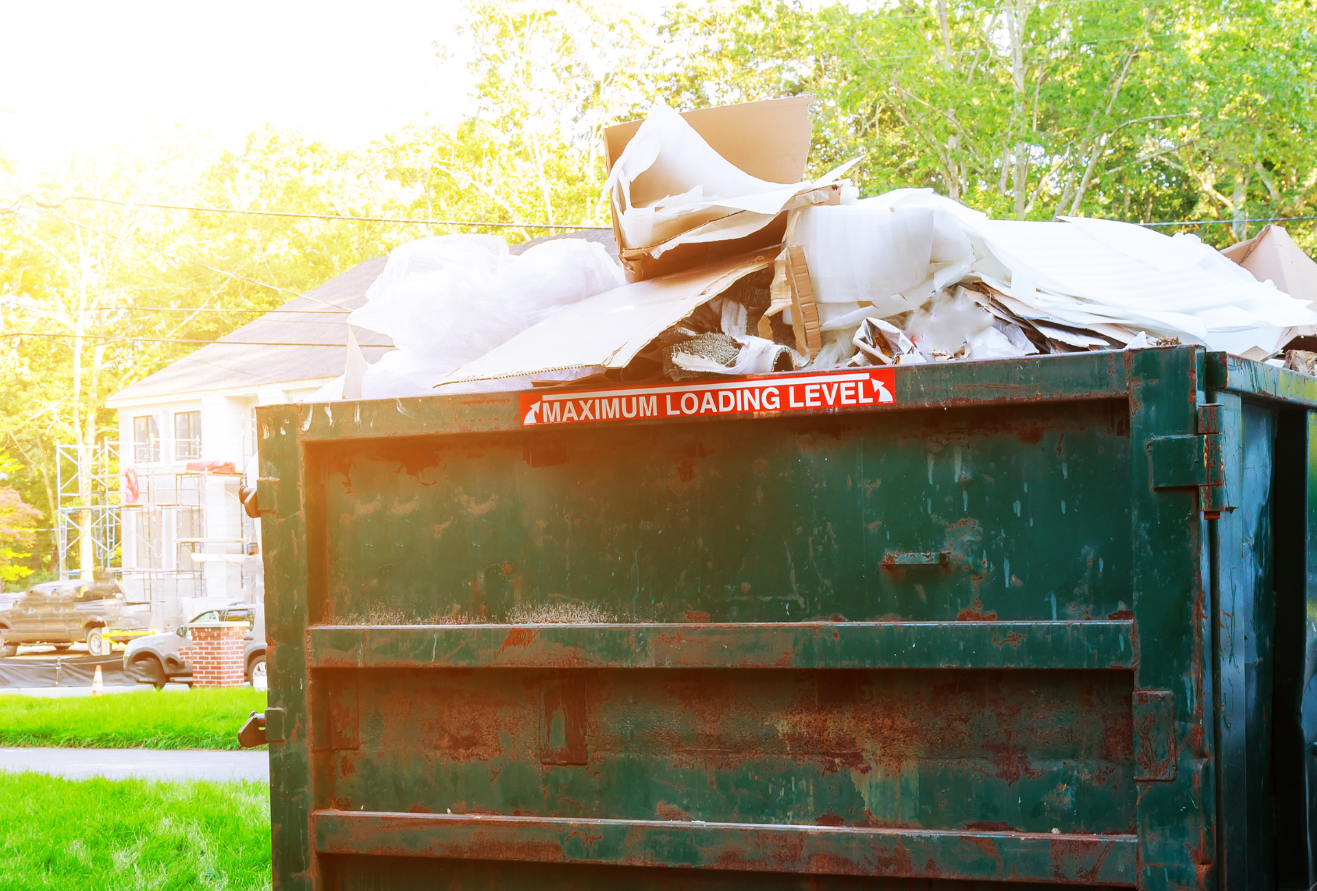 A dumpster filled with cardboard is sitting in front of a house.