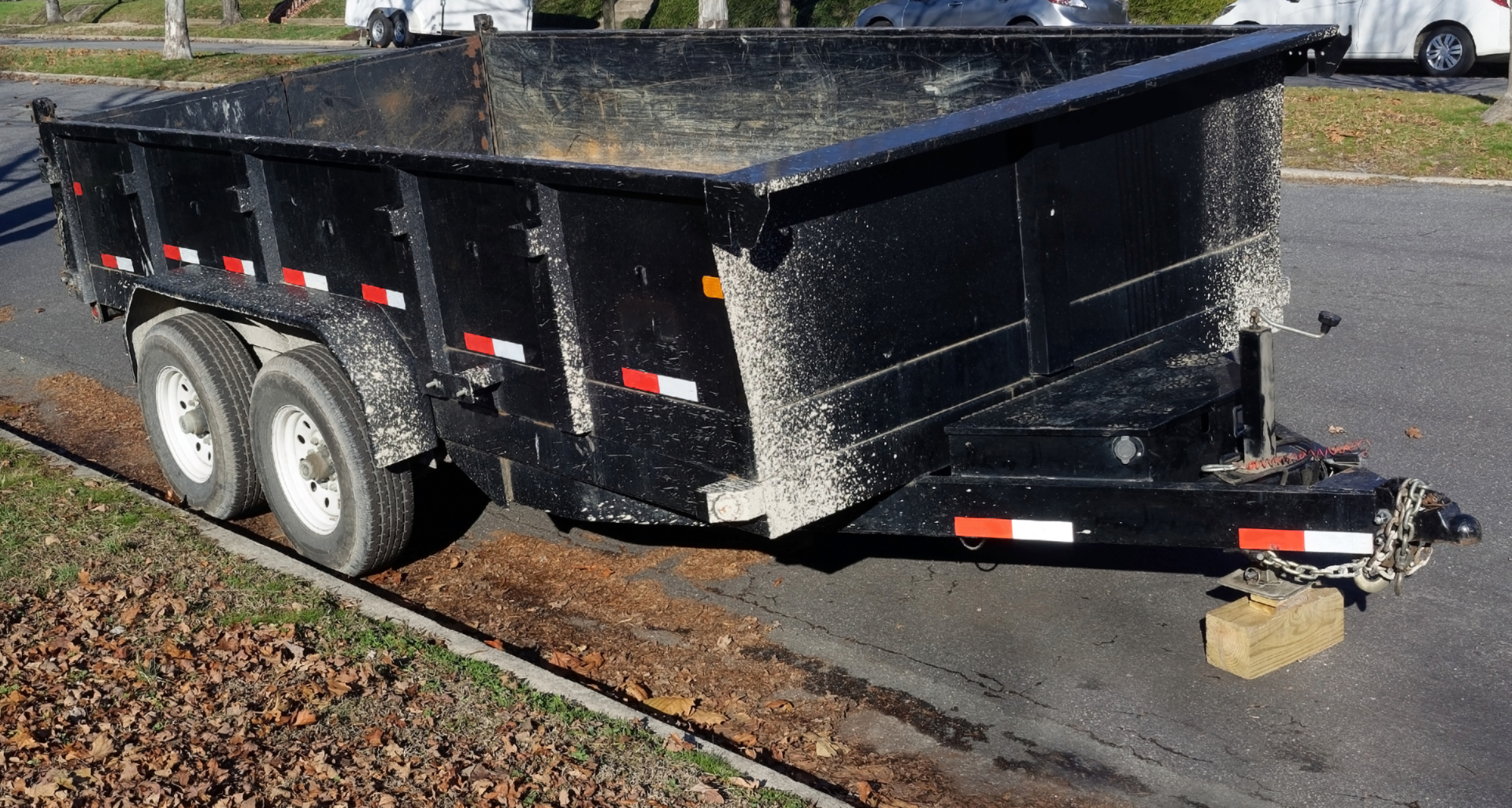 A dump trailer is parked on the side of the road.