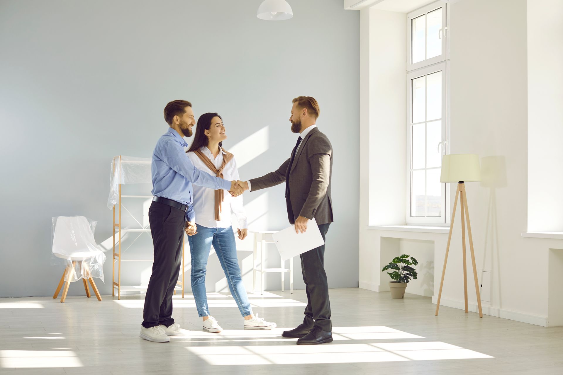 A Man and Woman Are Shaking Hands With a Real Estate Agent