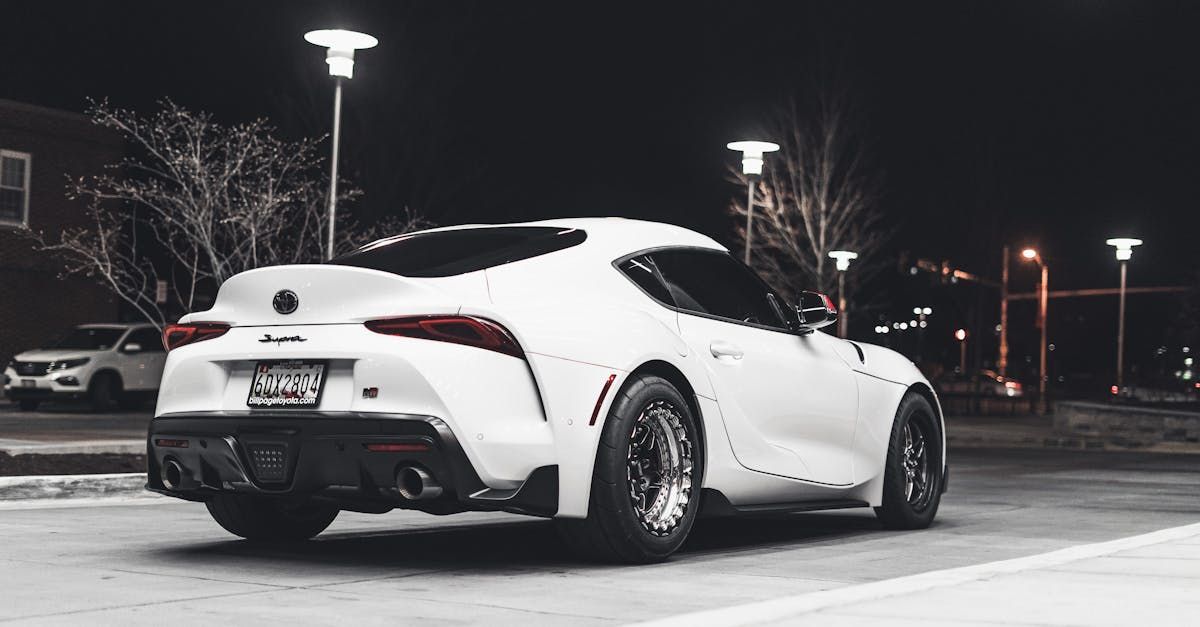 A white sports car is parked in a parking lot at night. | Faithful Service Auto