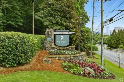A large stone sign is sitting in the middle of a lush green field.
