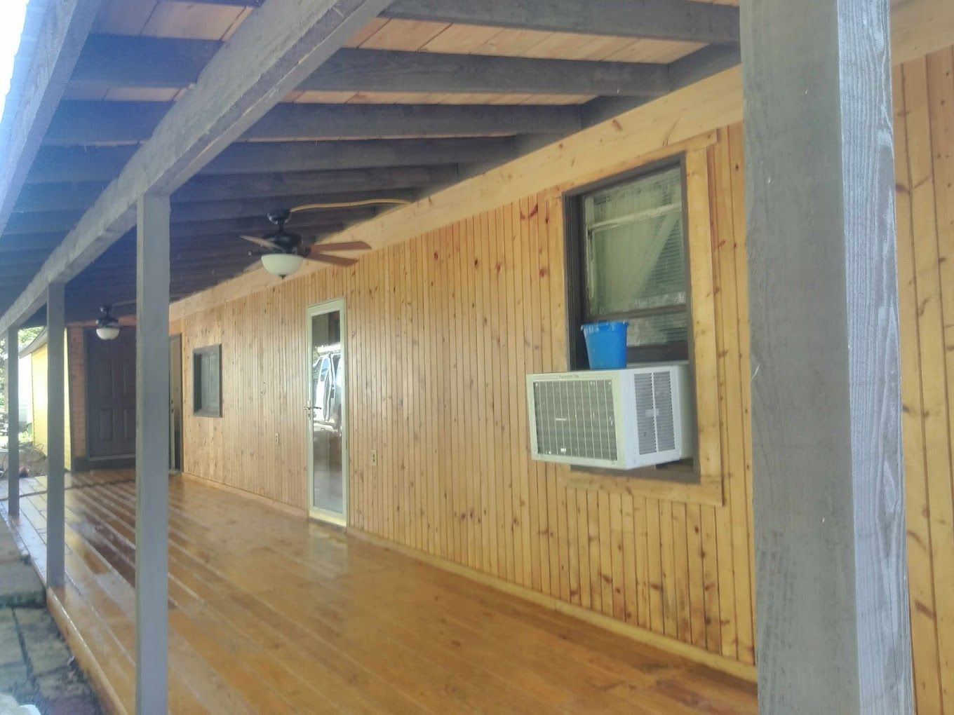 A wooden house with a porch and a window air conditioner