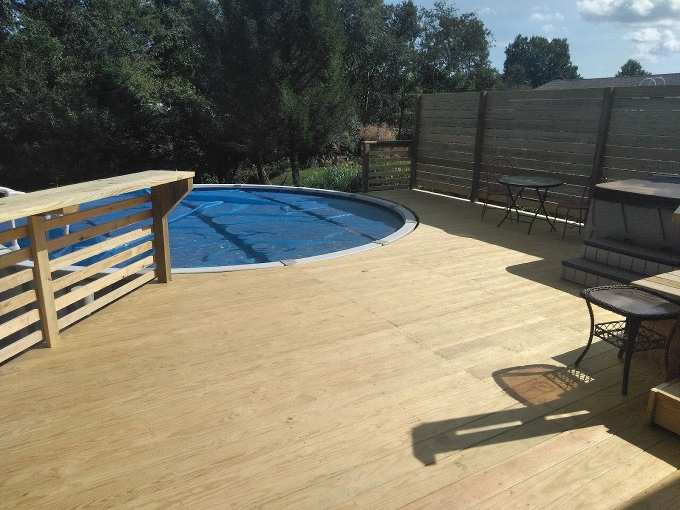 A wooden deck with a swimming pool in the background.