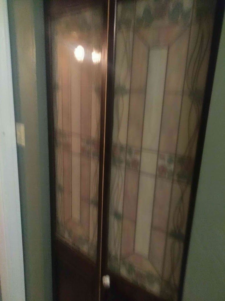 A stained glass door in a hallway with a light shining through it.