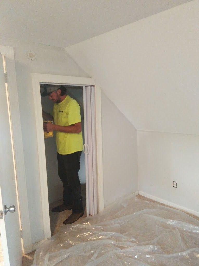 A man in a yellow shirt is standing in a room.