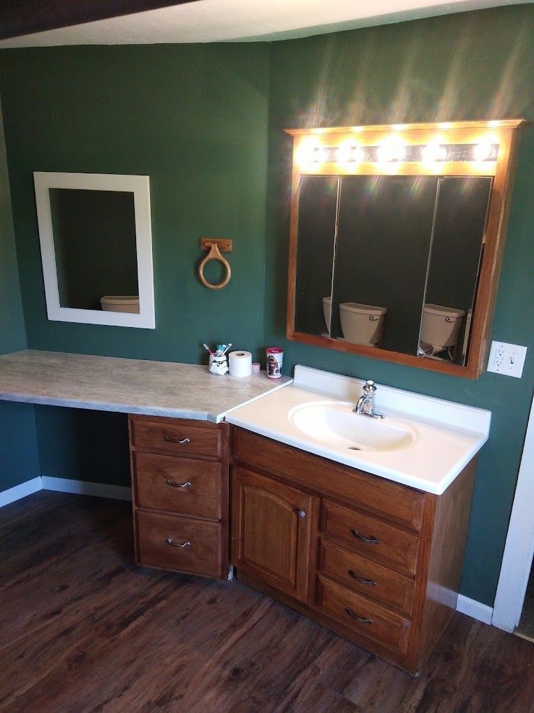 A bathroom with a sink , mirror , and wooden cabinets.