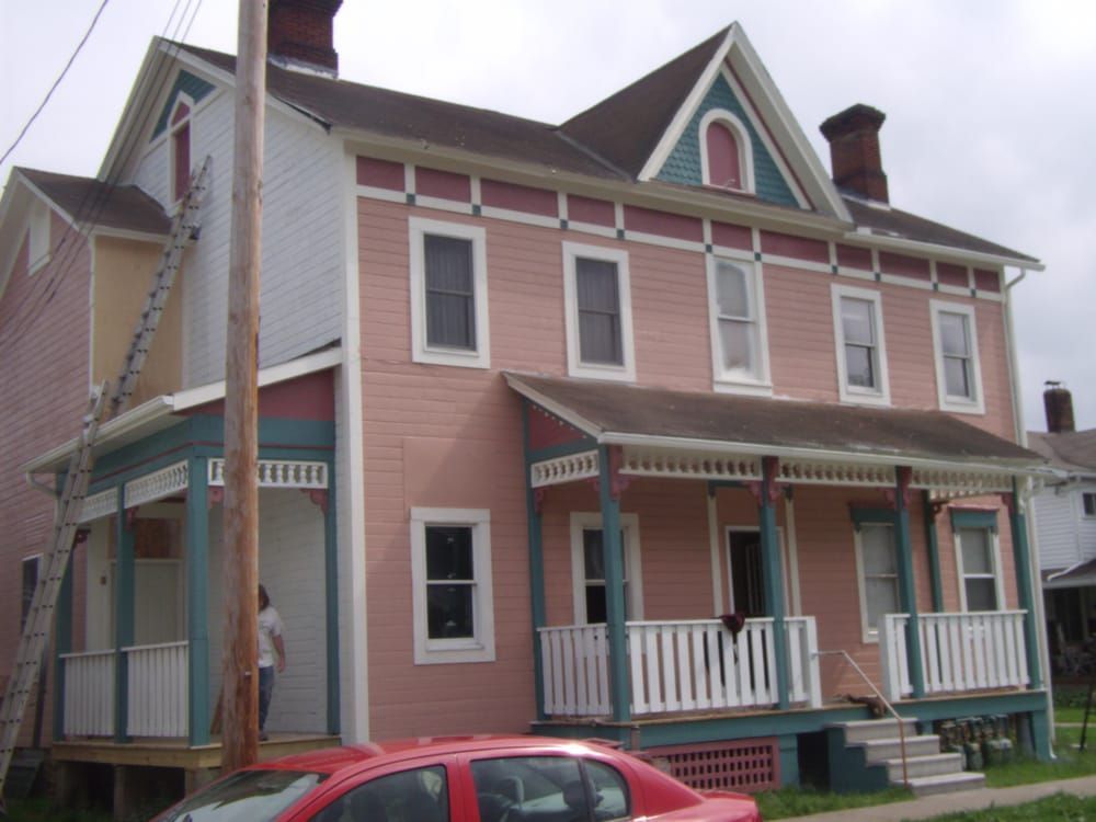 A pink house with a red car parked in front of it