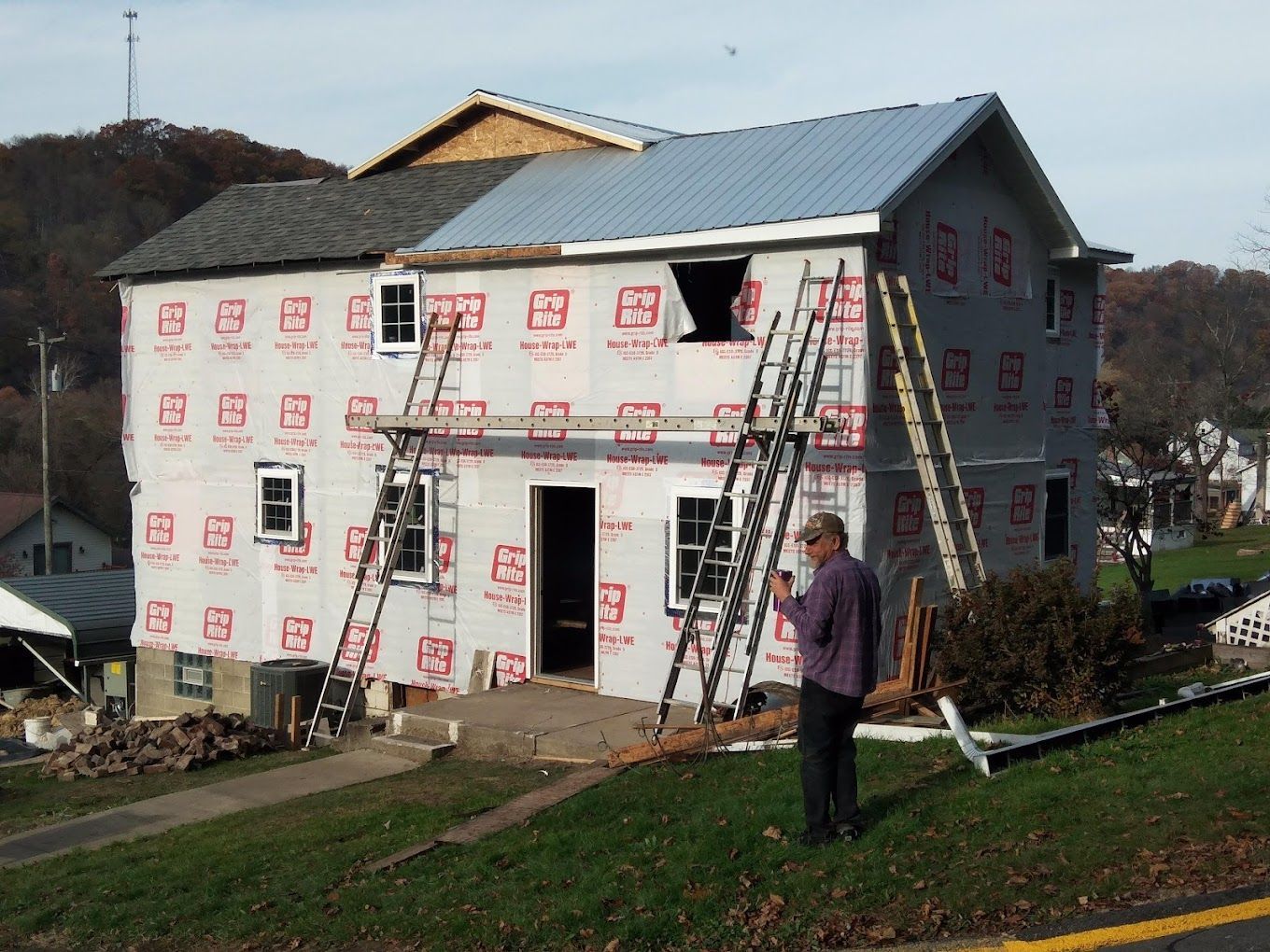 A man is standing in front of a house that is being built