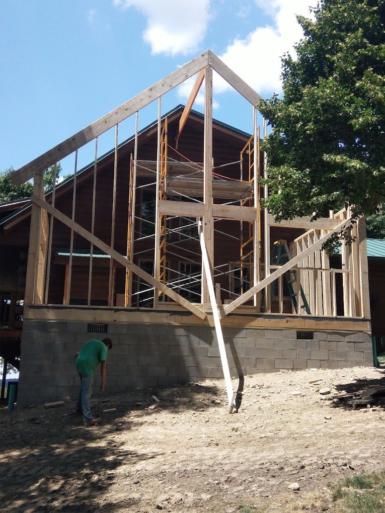 A man in a green shirt is standing in front of a building under construction